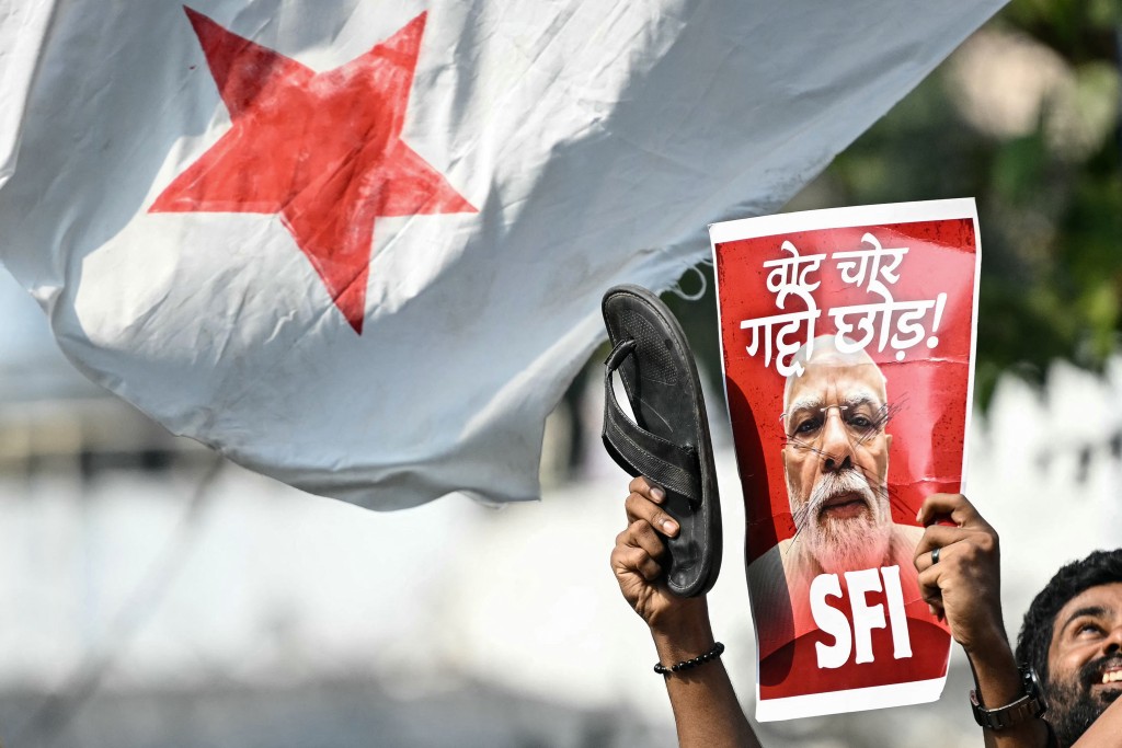 A student activist shows a poster of Inida's Prime Minister Narendra Modi during a protest demanding the resignation of the nation's Chief Election Commissioner Gyanesh Kumar over alleged voter roll irregularities linked to the "special intensive revision" (SIR), in New Delhi on October 14, 2026. (Photo by Arun SANKAR / AFP)