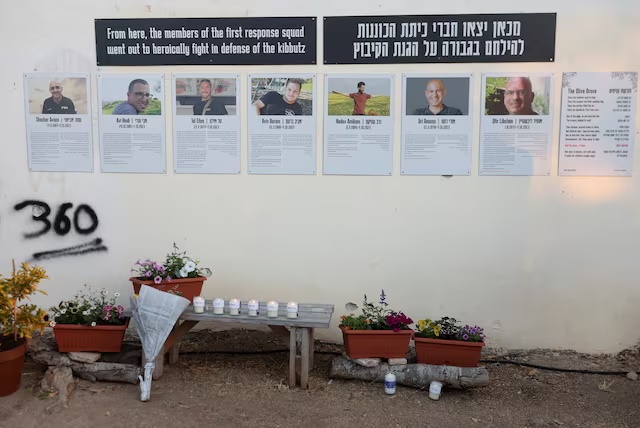 Flower tributes and candles are places in front of posters on a wall during a memorial to commemorate the two-year anniversary of the deadly October 7, 2023 attack on Israel by Hamas from Gaza, in Kibbutz Kfar Aza, southern Israel, October 7, 2025. REUTERS/Ronen Zvulun