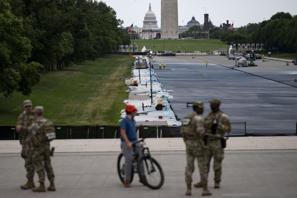 Photo by KENT NISHIMURA / AFP  A cyclist is seen next to National Guard members near the Lincoln Memorial Reflecting Pool as it is being resurfaced in Washington, DC, on May 13, 2026.