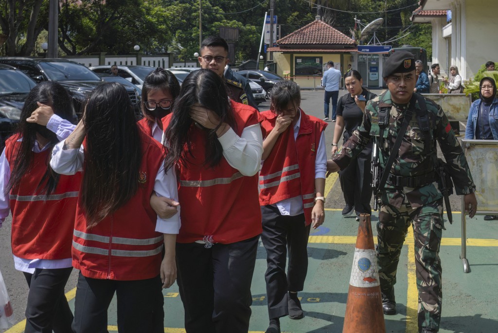 Photo by TIMUR MATAHARI / AFP An Indonesian military officer escorts defendants to a trial in a baby trafficking case at the Bandung District Court in Bandung, West Java, on July 21, 2026.