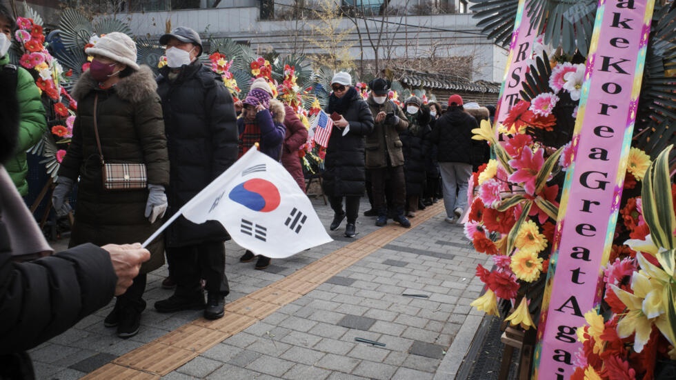 Supporters of impeached South Korean president Yoon Suk Yeol queue up for food beyond flowers outside his home © Anthony WALLACE / AFP Supporters of impeached South Korean president Yoon Suk Yeol queue up for food beyond flowers outside his home © Anthony WALLACE / AFP