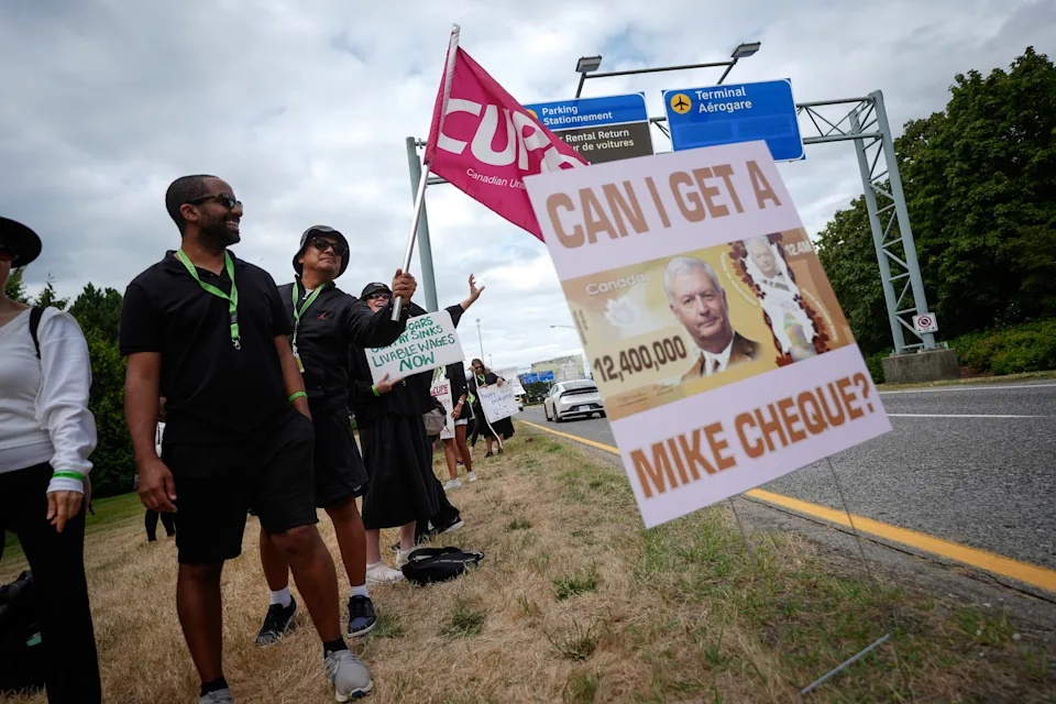 A sign with a photo of Air Canada CEO Michael Rousseau on it is seen as striking Air Canada flight attendants rally at Vancouver International Airport, in Richmond, British Columbia, Monday, Aug. 18, 2025. (/Darryl Dyck/The Canadian Press via AP)