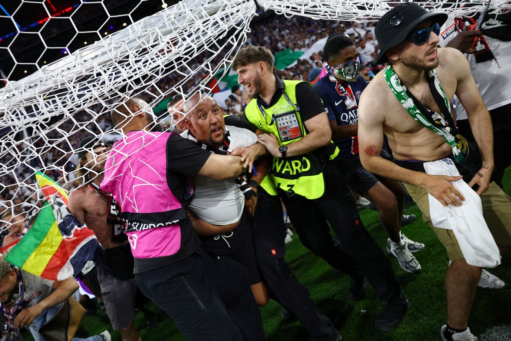 Stewards hold a pitch invader after the match. (Reuters)