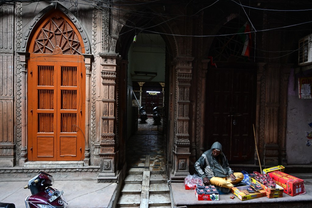 Photo by MANAN VATSYAYANA / AFP  This photograph taken on February 5, 2026 shows a vendor sitting outside a century-old haveli in the old quarters of Delhi.
