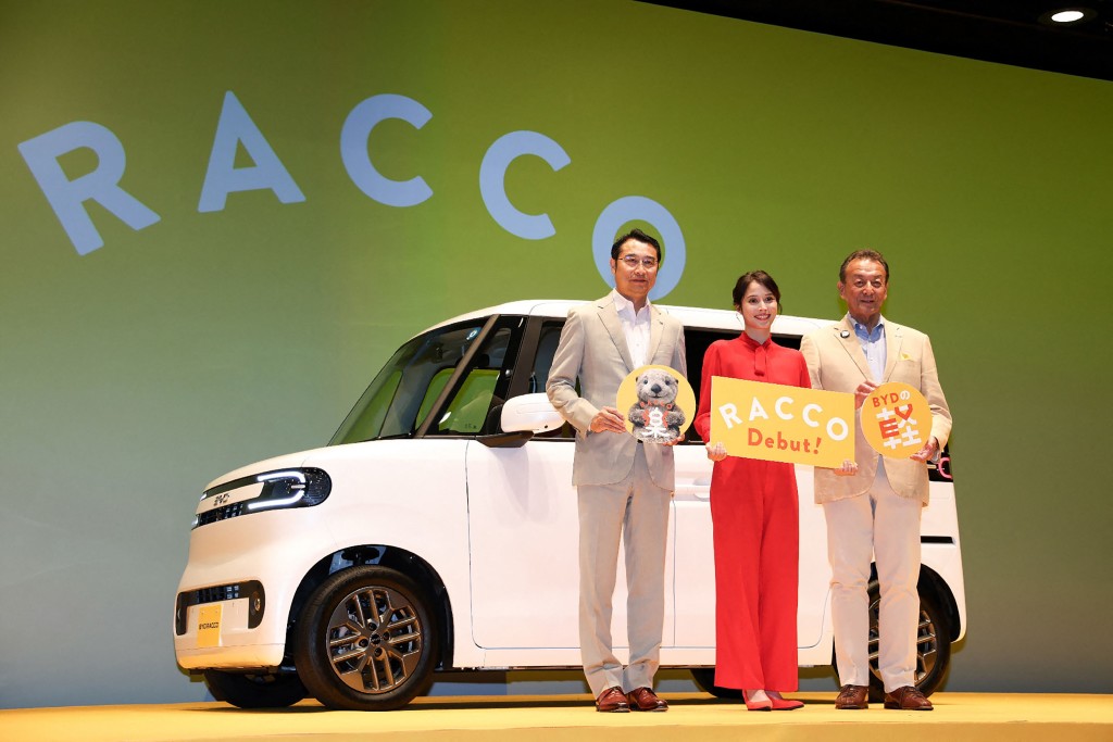 BYD Japan President Liu Xueliang (L) poses with actress Alice Hirose (C) during the launch of the BYD light electric vehicle "Racco" in Tokyo on July 28, 2026. BYD, which is also making major inroads in Europe and which in 2025 overtook Tesla as the world's biggest seller of EVs, said the Racco is the first "kei" car launched in Japan by an overseas automaker. (Photo by JIJI Press / AFP) / Japan OUT