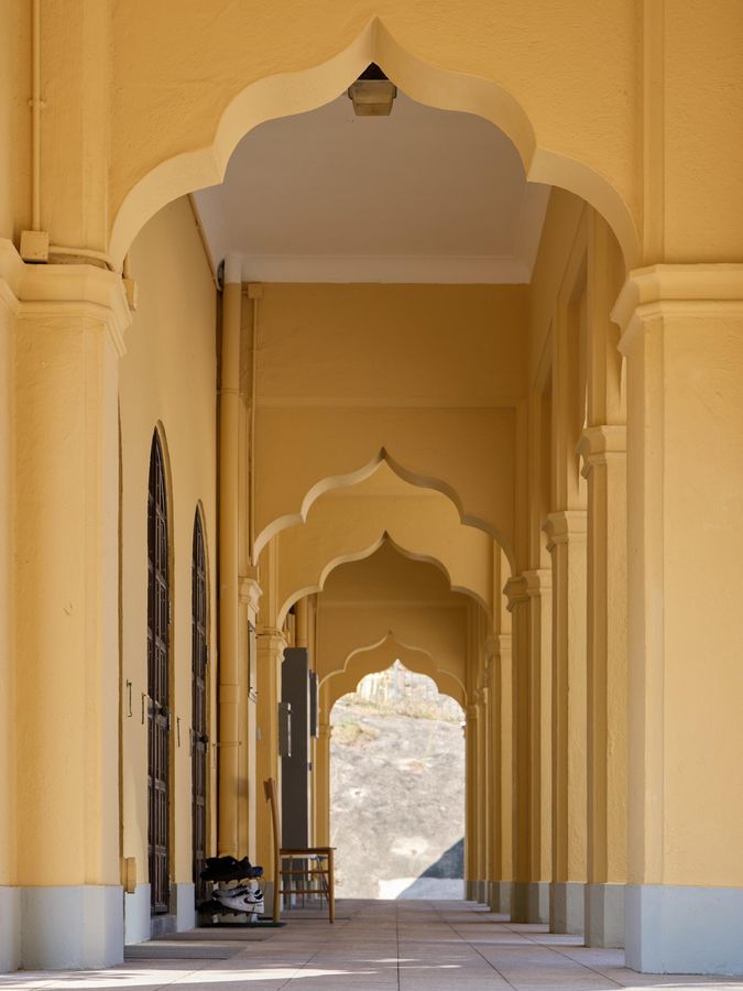Photo shows the mosque's open verandah with decorative ogee arches and moulding.