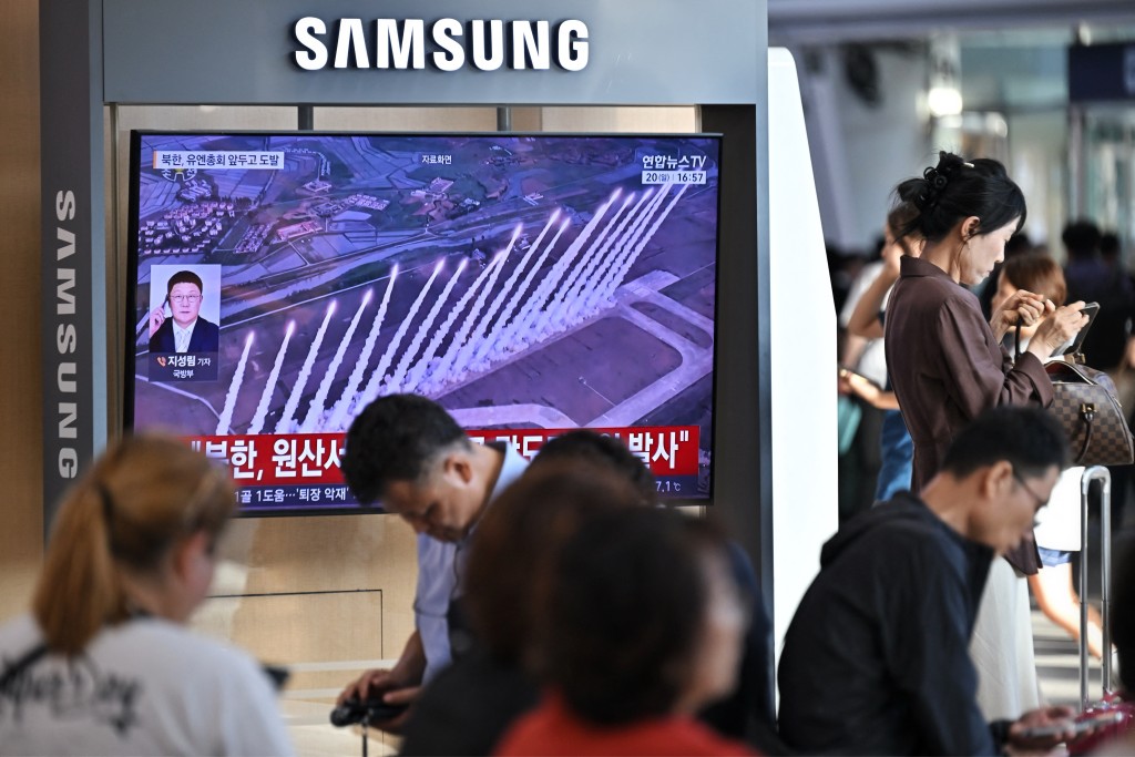 People sit near a television screen showing a news broadcast with file footage of a North Korean missile test, at a train station in Seoul on September 20, 2026. (AFP)