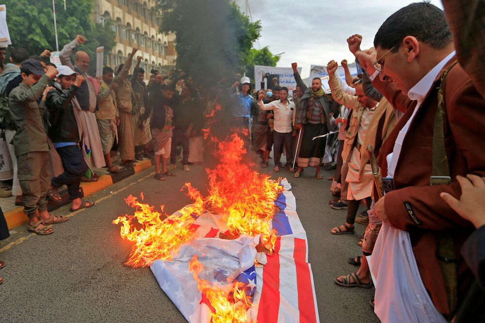 Supporters of Yemen's Houthi rebels burn a US flag during a rally marking the eighth anniversary of the Saudi-led intervention in their country in Sanaa on March 26, 2023. (AFP)   
