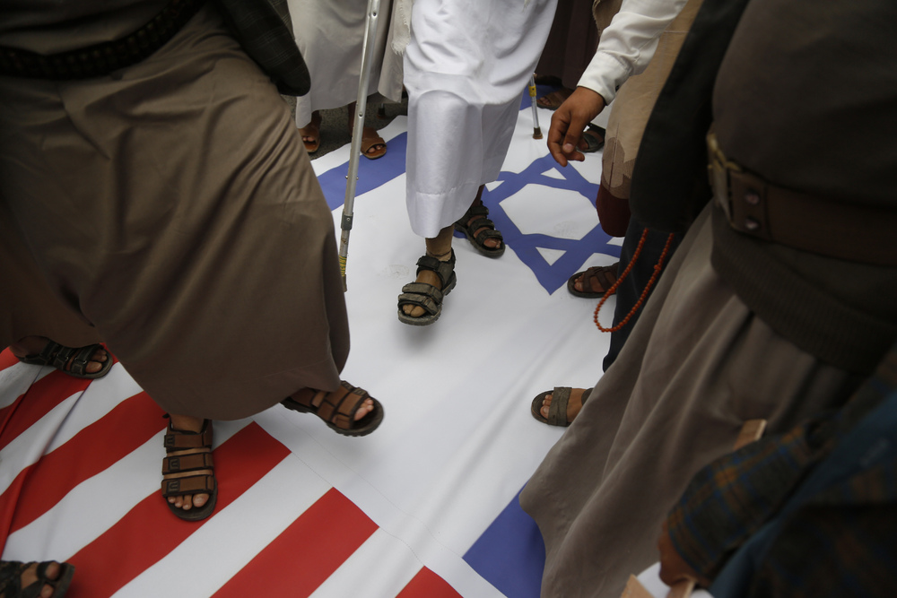 Houthi supporters trample on representation of the US and Israeli flags during a rally marking eight years for a Saudi-led coalition, Friday, March 26, 2023, in Sanaa, Yemen. (AP)   