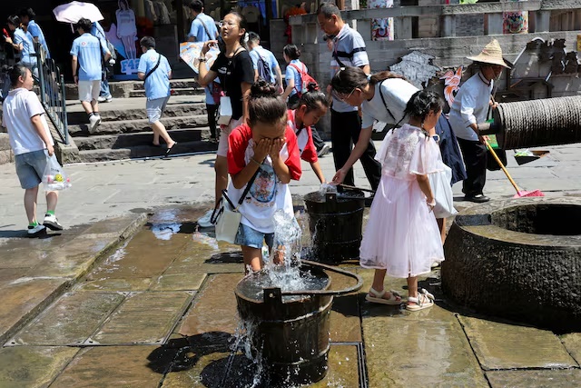 A child rinses her face with water from the fountain to cool off amid a red alert for heat in Chongqing, China, July 31, 2025. REUTERS/Go Nakamura