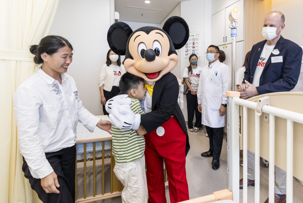 Mickey Mouse visits a ward to offer warm blessings to a young patient.