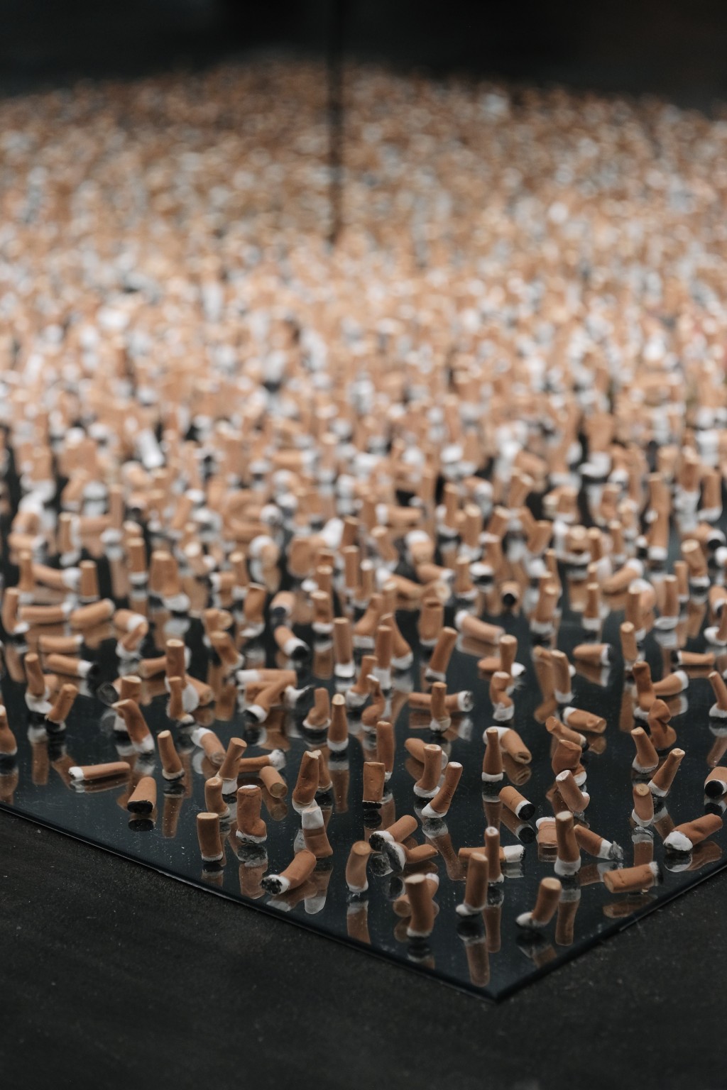 More than 800 hand-shaped ceramic cigarette butts capture traces of exhausted goodbyes and suspended moments where private emotion quietly lingers in public space.