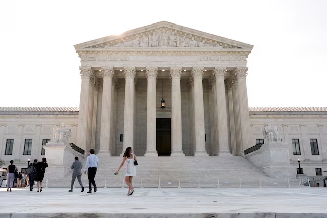 People walk in front of the Supreme Court building, as the court is set to issue the final rulings of its nine-month term, in Washington, D.C., U.S., June 30, 2026. REUTERS/Cheney Orr