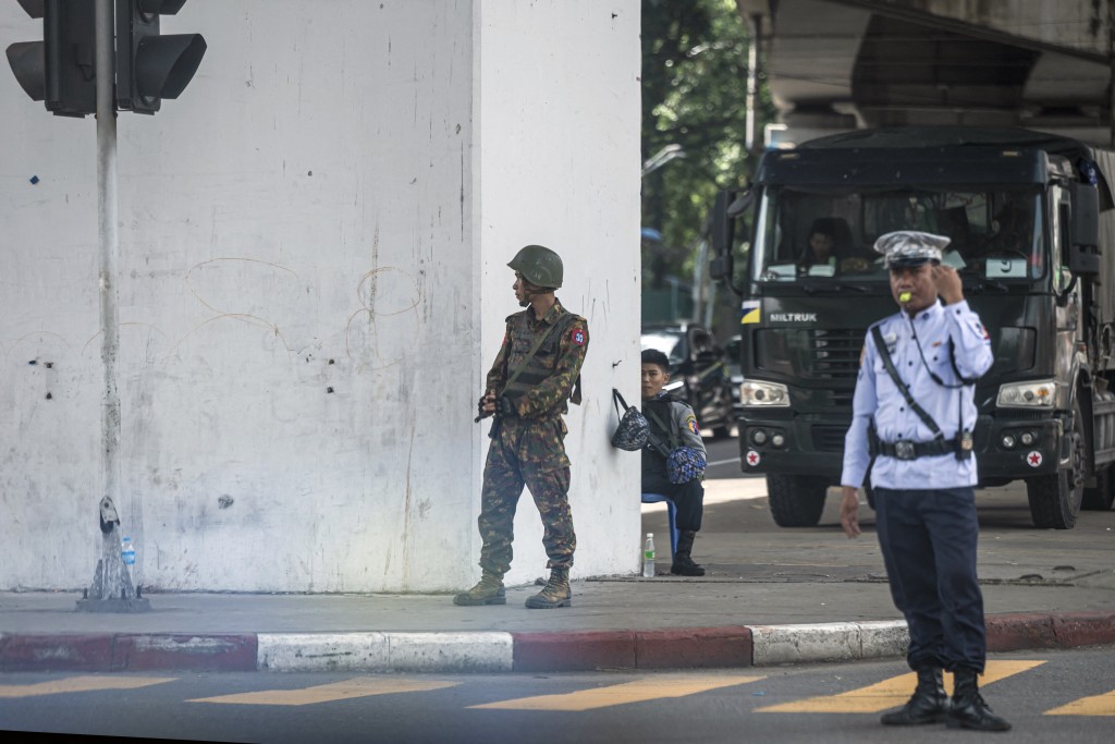 A soldier keeps watch as police control traffic on a street in Yangon on July 19, 2026, on the 79th Martyrs' Day that marks the anniversary of the assassination of independence leaders, including general Aung San, father of the currently deposed and imprisoned leader Aung San Suu Kyi. (Photo by Sai Aung MAIN / AFP)