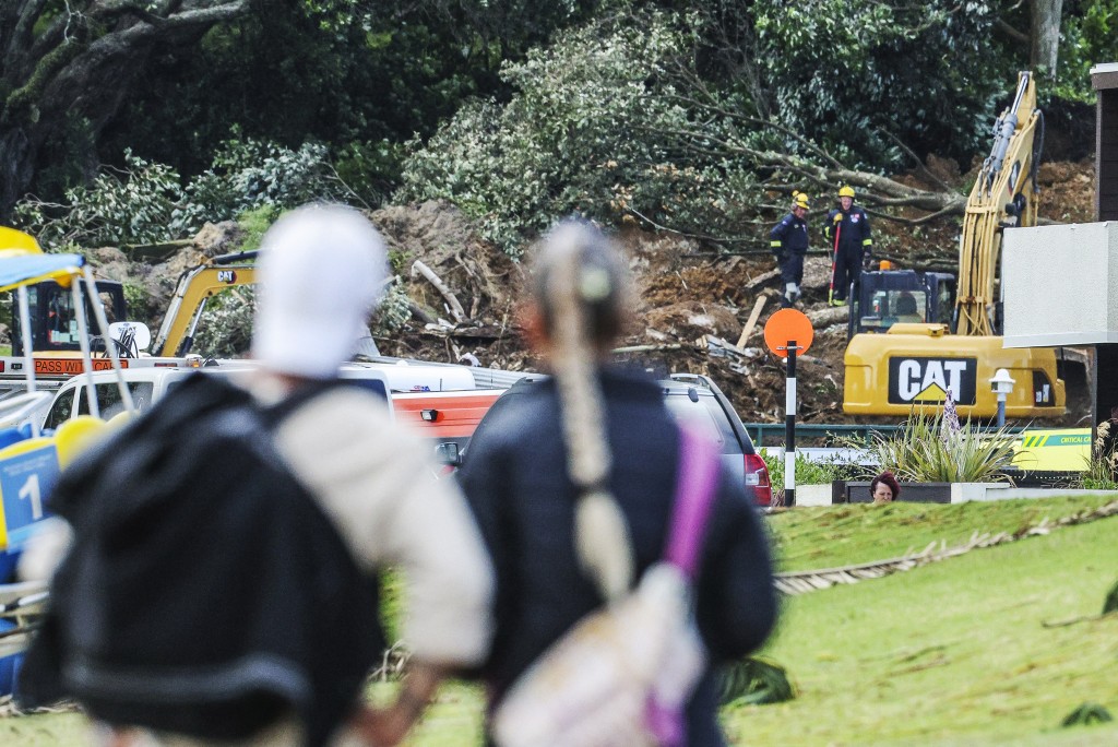 Photo by DJ MILLS / AFP  A couple looks at a landslide while a search is underway by local emergency services for missing people at Mount Maunganui in Tauranga on January 22, 2026.