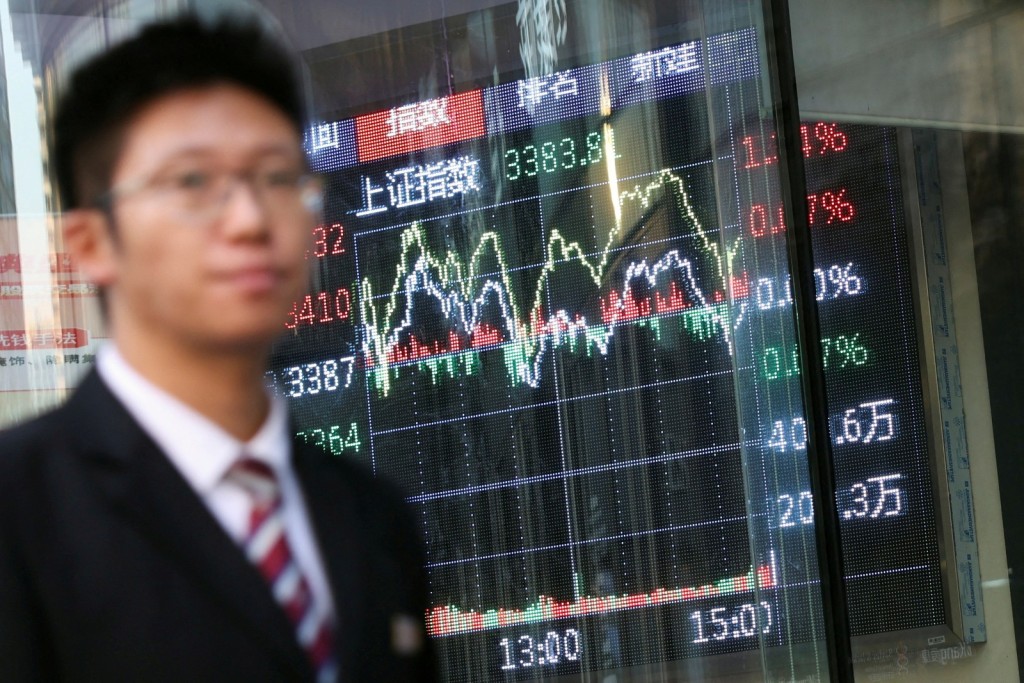 A man walks past a brokerage house with a display board showing the Shanghai Composite Index and other stock information, in Beijing, China. Reuters