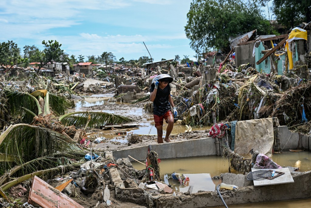 A resident walks along damaged houses in the aftermath of Typhoon Kalmaegi in Talisay, in the province of Cebu on November 5, 2025. (Photo by Jam STA ROSA / AFP)