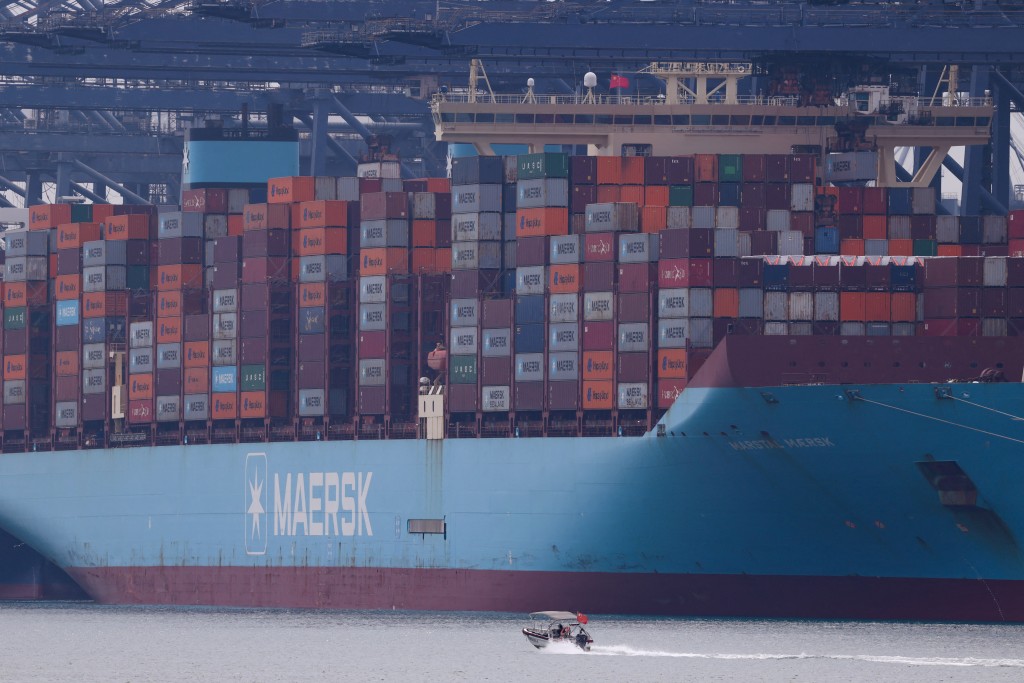 A boat moves past a cargo ship with containers at a terminal of the Yantian port in Shenzhen, Guangdong province, China October 30, 2025. REUTERS/Tingshu Wang