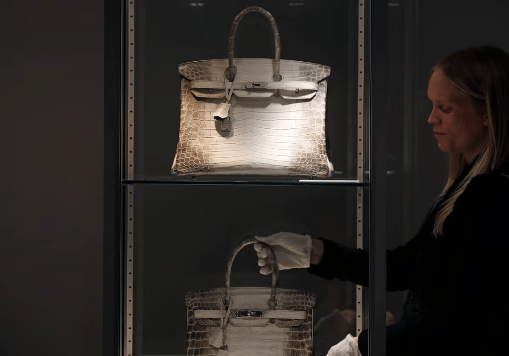 A staff member poses next to rare Hermes handbags, the mat white Birkin Himalaya 35 (top) and Birkin Himalaya 30 during an auction preview at Christie's in Paris, France, March 4, 2016. REUTERS/Christian Hartmann