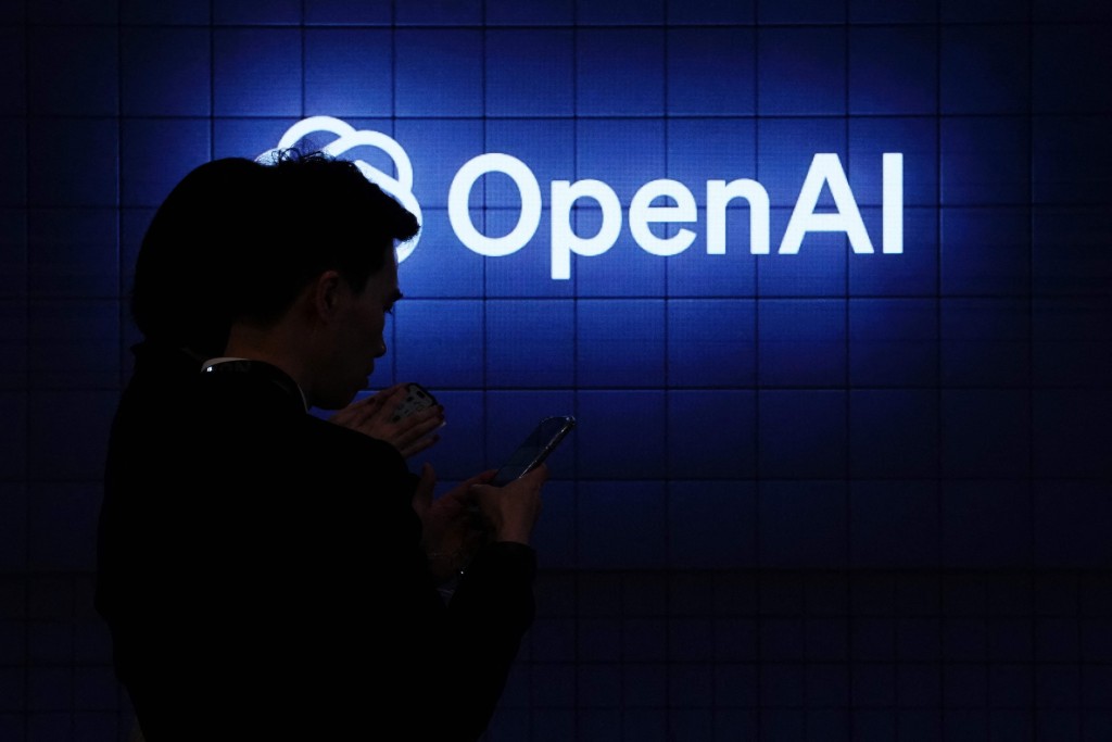 Visitor look at their phone next to an Open AI's logo during the Mobile World Congress (MWC), the telecom industry's biggest annual gathering, in Barcelona on February 26, 2024. AFP