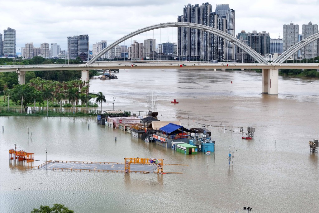 Photo by - / CN-STR / AFP  Flooded shops along a submerged riverside walk are seen by the overflowing Yongjiang river in Nanning, in China’s southern Guangxi region on July 7, 2026.