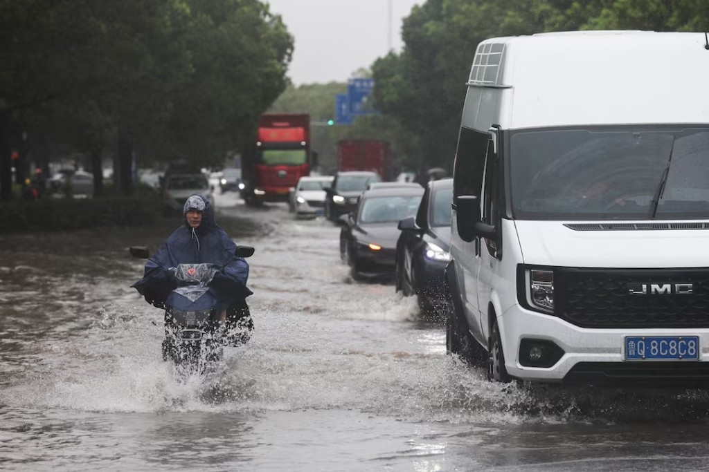 A person rides an electric bike through a flooded street after Typhoon Dolphin brought heavy rain to Shanghai, China, August 10, 2026. REUTERS/Go Nakamura 