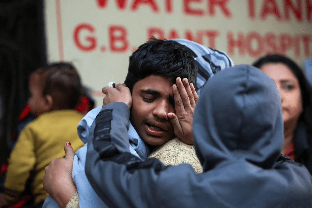 Son of Dinesh Mishra, who died in a deadly explosion near the historic Red Fort in the old quarters of Delhi, cries as he comforted by people outside a mortuary at a hospital, in Delhi, India, November 11, 2025. REUTERS/Anushree Fadnavis