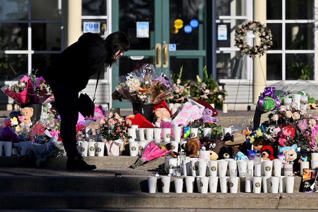 A woman visits a growing makeshift memorial on the steps of the town hall, four days after one of the worst mass shootings in recent Canadian history, in the town of Tumbler Ridge, British Columbia, Canada, February 14, 2026. REUTERS/Jennifer Gauthier/File Photo