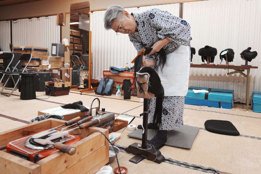 Photo by KAZUHIRO NOGI / AFP  This photo taken on March 11, 2026 shows wig master Tadashi Kamoji creating a wig for kabuki actors at his atelier in Tokyo.