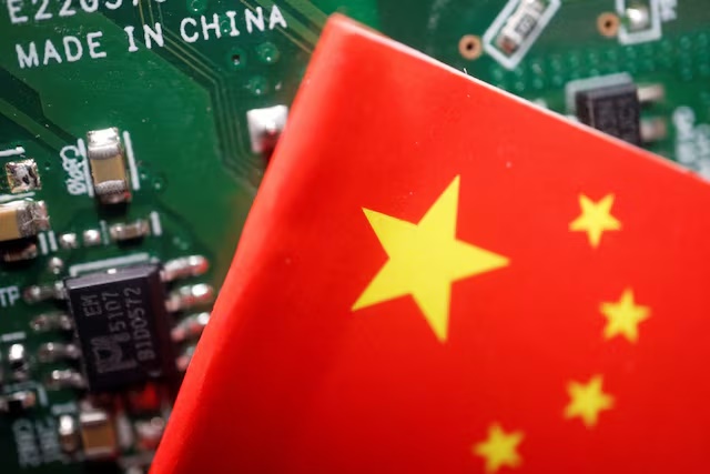 A Chinese flag is displayed next to a "Made in China" sign seen on a printed circuit board with semiconductor chips, in this illustration picture taken February 17, 2023. REUTERS/Florence Lo/Illustration