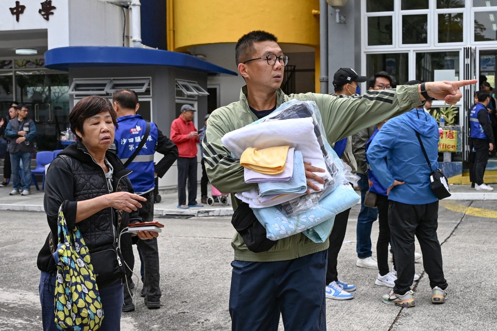 Photo by PETER PARKS / AFP  A resident collects blankets and towels at the Fung Leung Kit Secondary School, one of the community centres allocated for affected residents after a major fire swept through several apartment blocks at the Wang Fuk Court residential estate in Hong Kong's Tai Po district on November 27, 2025.
