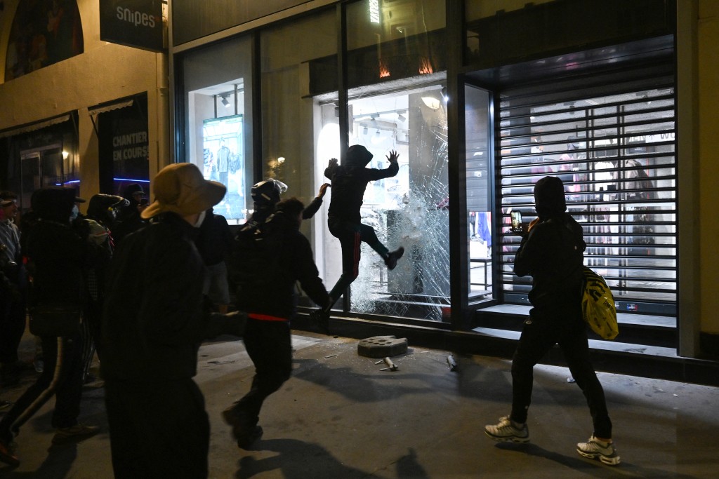 People try to destroy the window of a Snipes store near Chatelet - Les Halles as clashes erupted at Place de la Republique following an unauthorised demonstration, central Paris, on October 18, 2026 a day after nationwide protests against the "high cost of living". (AFP)