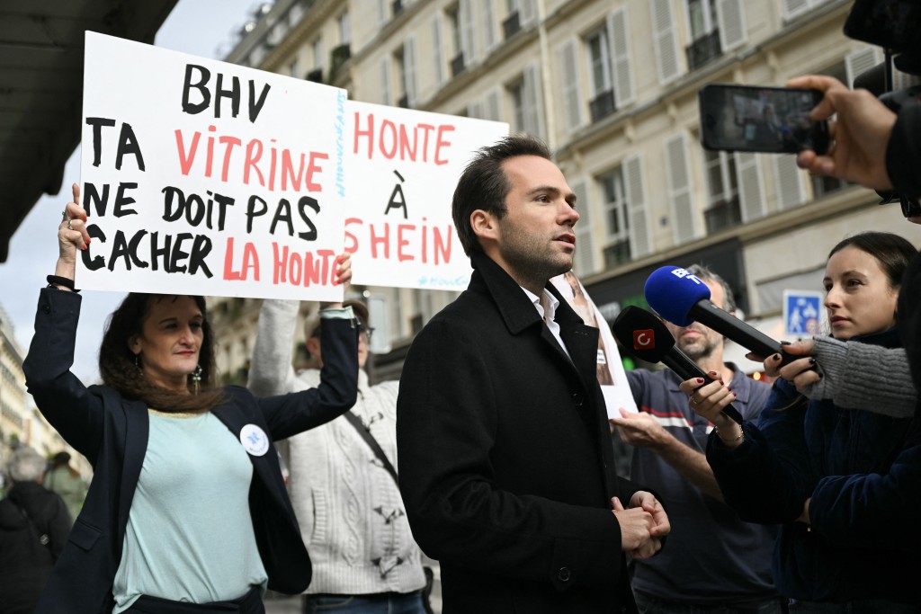 Photo by JULIE SEBADELHA / AFP  Director of Bazar de l'Hotel de Ville (BHV) Karl Cottendin (C) addresses media during a protest of activists belonging to Mouv'Enfants, a movement fighting against all forms of violence against children, in front of the Parisian department store in Paris on November 3, 2025, after Chinese company Shein was selling on its online platform dolls of a likely "child pornography nature".