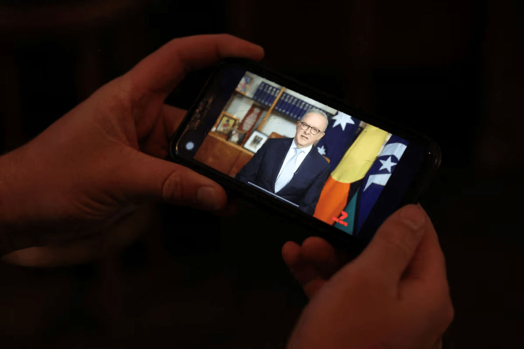 A pub-goer watches Australian Prime Minister Anthony Albanese deliver his address to the nation over the Iran crisis, on his phone at a pub in Sydney, Australia, April 1 2026. REUTERS/Hollie Adams