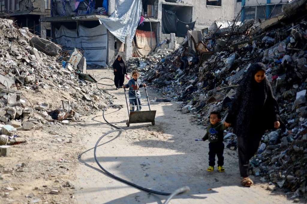 Palestinians walk past the rubble of residential buildings destroyed during the war, in Jabalia, northern Gaza Strip, January 6, 2026. REUTERS/Mahmoud Issa/File Photo