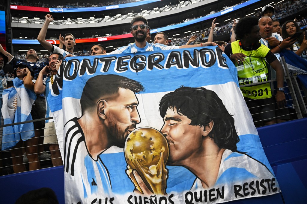 An Argentina supporter holds a flag depicting late Argentine football player Diego Maradona and Argentina's forward #10 Lionel Messi after the during the 2026 World Cup Group J football match between Argentina and Austria at the Dallas Stadium in Arlington on June 22, 2026. (Photo by Paul ELLIS / AFP)