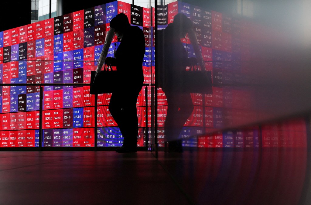 A man walks in front of an electronic screen displaying Japan's Nikkei stock prices quotation board inside a conference hall in Tokyo, Japan, April 27, 2026. REUTERS