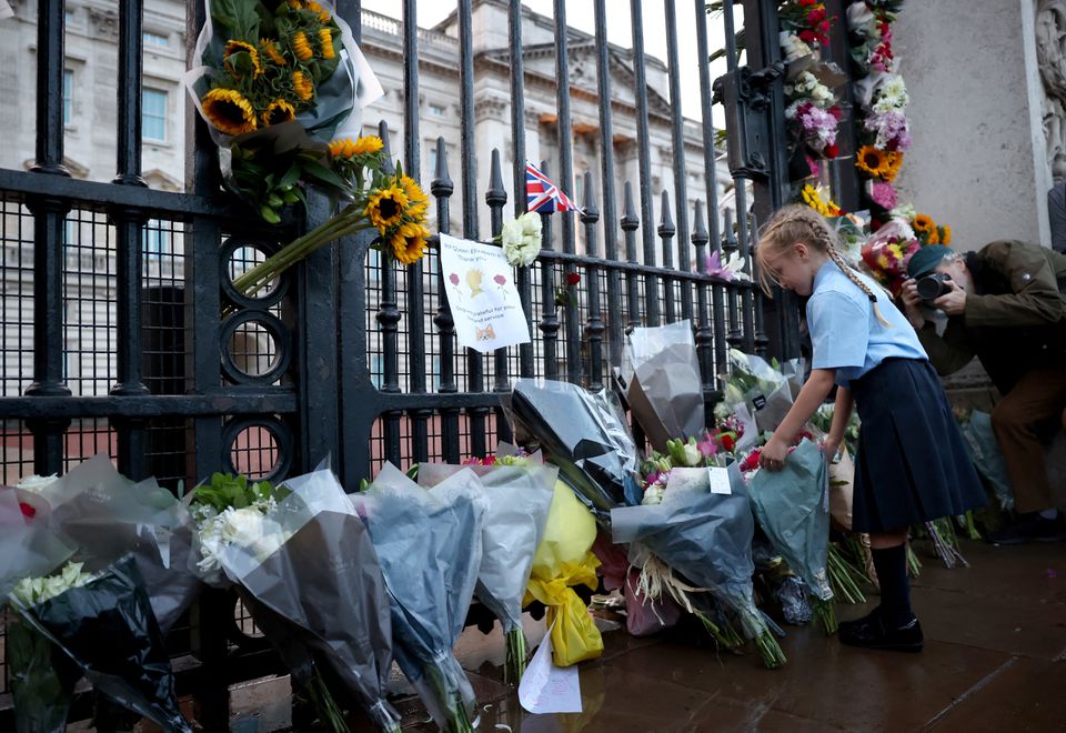 A girl places flowers outside Buckingham Palace, after Queen Elizabeth, Britain's longest-reigning monarch and the nation's figurehead for seven decades, died aged 96. (Reuters) A girl places flowers outside Buckingham Palace, after Queen Elizabeth, Britain's longest-reigning monarch and the nation's figurehead for seven decades, died aged 96. (Reuters)