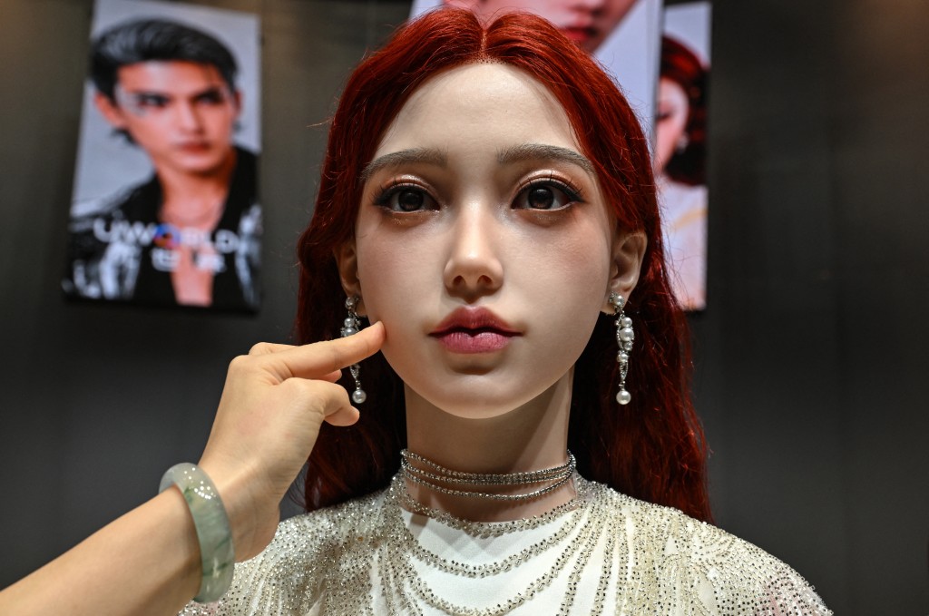 Photo by ADEK BERRY / AFP  A woman touches the face of a humanoid robot during the launch of the U1 humanoid robot produced by UWORLD, a brand under UBTECH Robotics, in Shenzhen, China's Guangdong province on June 30, 2026.