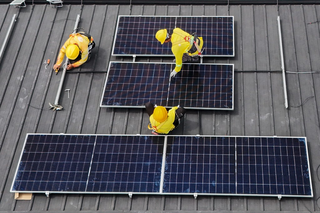 Photo by JAM STA ROSA / AFP This aerial photo taken on July 9, 2026 shows workers installing solar panels on a roof in Carmona, in the Philippine province of Cavite.