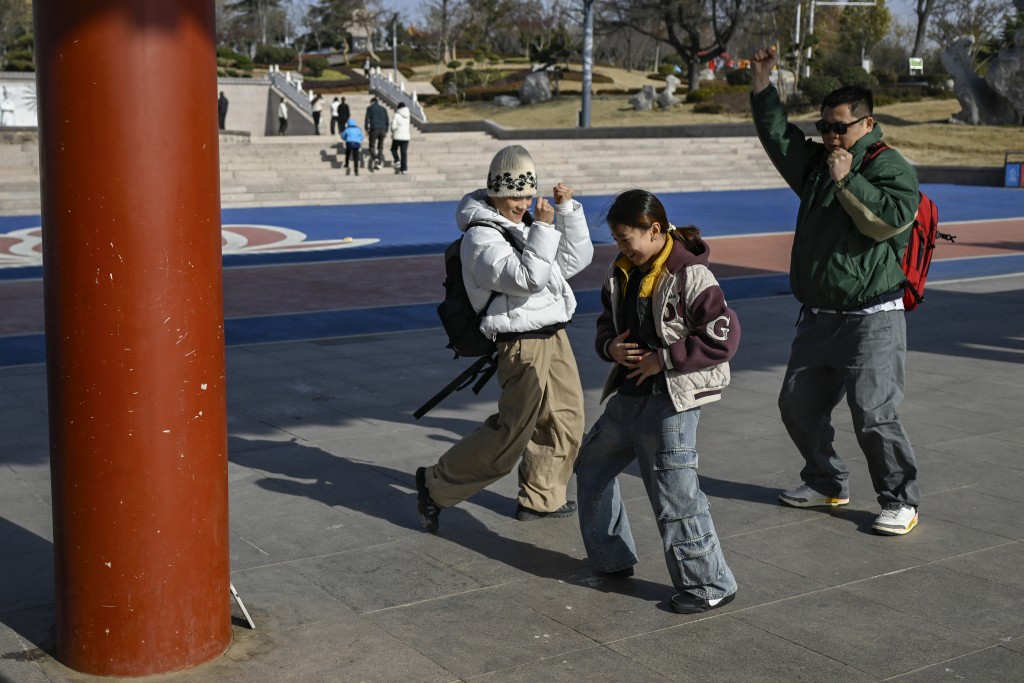 Photo by WANG ZHAO / AFP This picture taken on November 26, 2025 shows Guo Pu (L) dancing with her coach Li Shilong (R) and teammate Deng Siqi (C) for a Douyin (TikTok) video at a park in Pingyi county, in eastern China's Shandong province.