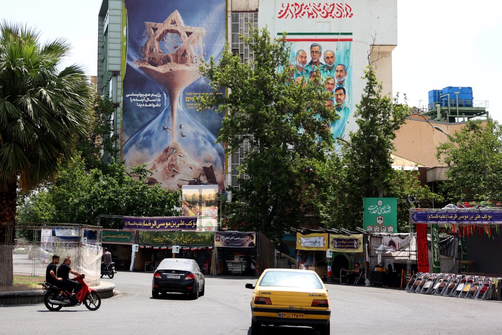 Iranians drive next to an anti-Israeli billboard carrying the sentence reading in Farsi, "Israel would not see the next 15 years" erected on the side of a building in Palestine Square in Tehran, on May 28, 2026. (AFP)