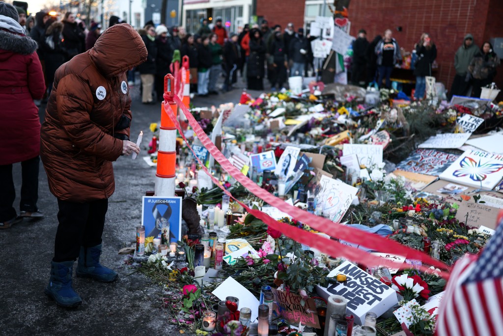 People pay homage to Alex Pretti at the makeshift memorial set up near the street where he was shot and killed by federal immigration agents in Minneapolis, Minnesota, on January 31, 2026. (AFP)