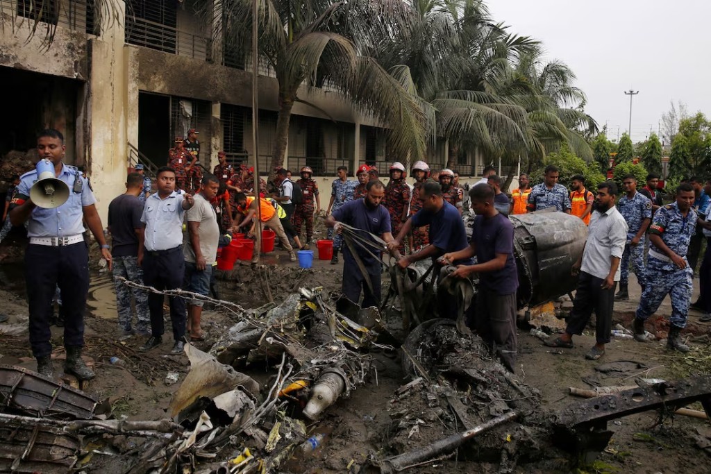 Firefighters work to remove the wreckage from a building, after an air force training aircraft crashed into Milestone College campus, in Dhaka, Bangladesh, July 21, 2025. REUTERS/Stringer