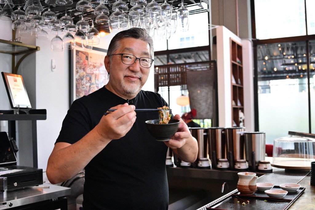 Photo by FREDERIC J. BROWN / AFP This photo taken on May 14, 2026 shows Kenji Suzuki, second-generation owner of Suehiro Japanese Restaurant in Los Angeles, holding a bowl of natto at his establishment.