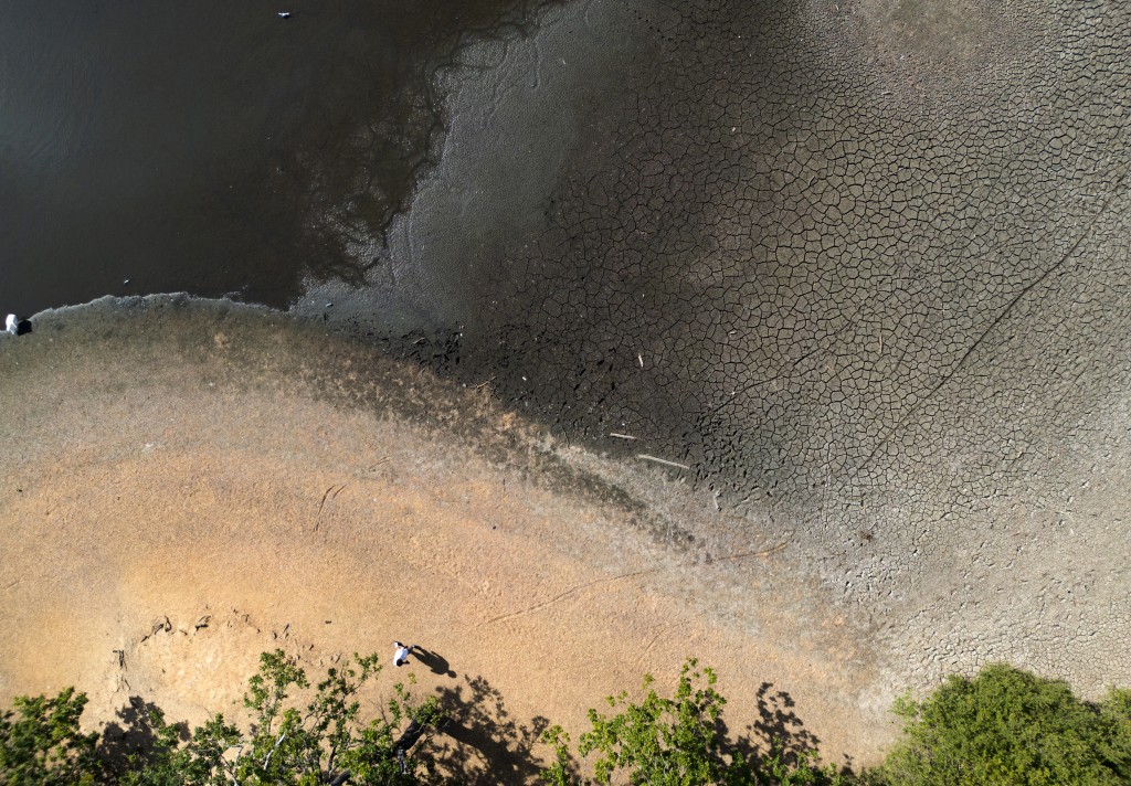 TOPSHOT - An aerial view shows the dried and cracked bed of the depleted Hollow Pond and Leyton flats near Wanstead, east London, on August 10, 2026, following weeks of hot, dry weather, leading to more than half of England being declared in a drought. (Photo by HENRY NICHOLLS / AFP)