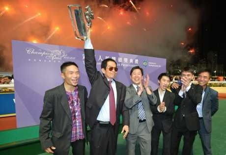 The legendary former trainer Brian Kan lifts the 2012/13 Trainers' Championship trophy next to the winner Dennis Yip (Sing Tao) 
