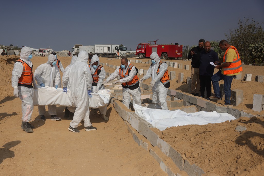 Photo by BASHAR TALEB / AFP. Health and civilian workers conduct a mass burial of Palestinians at a cemetery in Khan Yunis, in the southern Gaza Strip, on November 10, 2025.