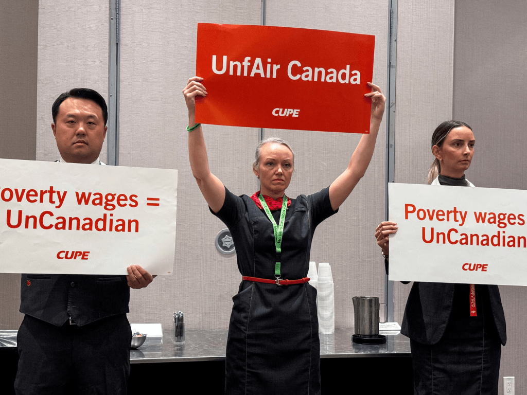 Union activists hold placards, as they interrupt a press conference by Air Canada executives, ahead of a potential strike by Air Canada flight attendants, at a hotel in Toronto, Ontario, Canada, August 14, 2025. REUTERS/Kyaw Soe Oo/File Photo 
