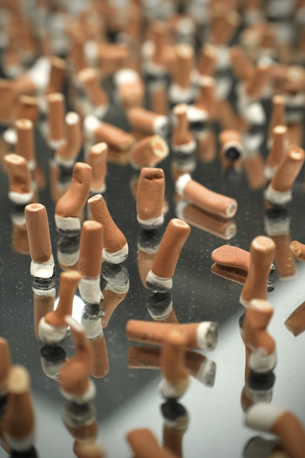 More than 800 hand-shaped ceramic cigarette butts capture traces of exhausted goodbyes and suspended moments where private emotion quietly lingers in public space.